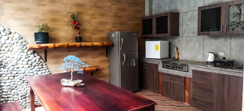 Cocina compartida con una mesa de madera, refrigerador y encimera.