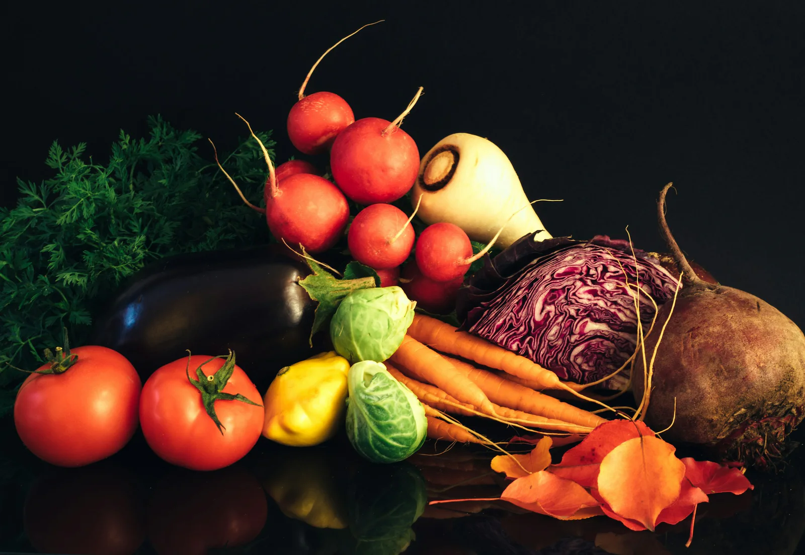 Verduras y hortalizas frescas dispuestas sobre una superficie oscura.